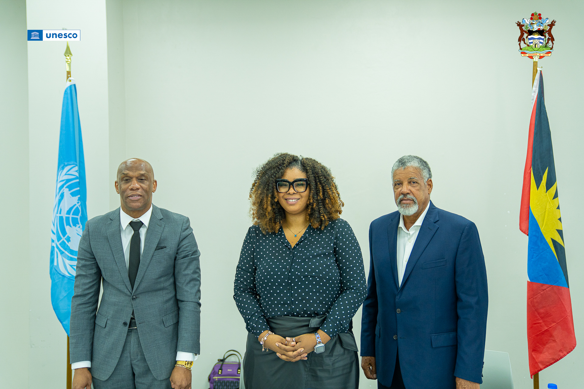 From left to right, Mr. Clare Browne, Mrs. Andrea Andrew and Dr. Reginald Murphy pose for a photo flanked left to right by the UN and Antigua and Barbudan flags.